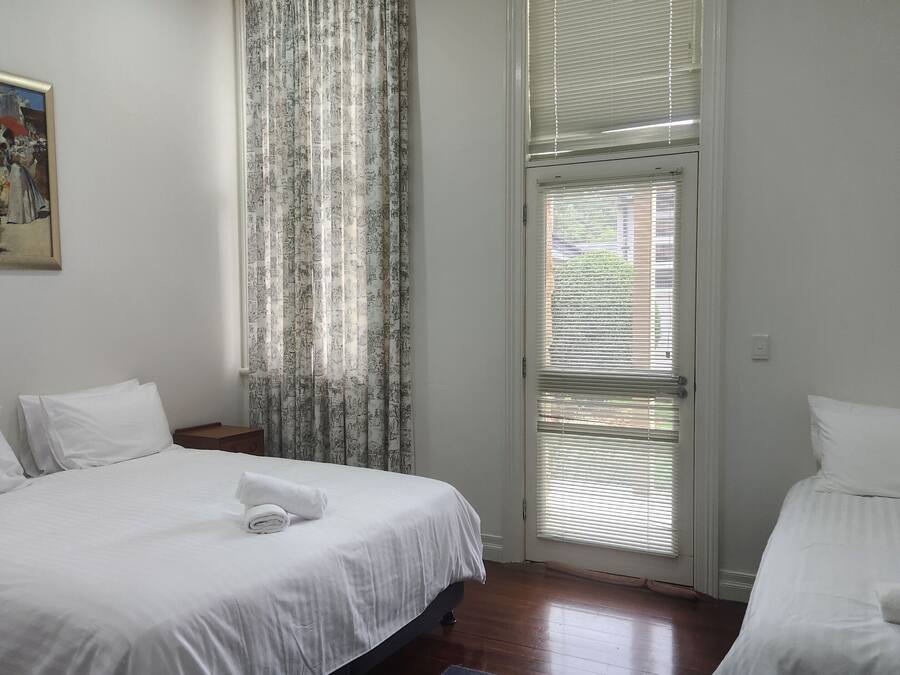 Ett hotellrum med två sängar, en tavla på väggen och ett fönster med persienner.