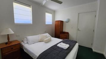 A hotel room with a bed, a nightstand with a lamp, a wardrobe, and a door.