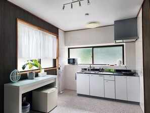 Eine moderne Küche mit weißen Schränken, einer Mikrowelle, einem Wasserkocher und einem kleinen Kühlschrank.