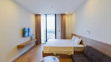 A hotel room with a bed, a TV, a sofa, and a view of the city.