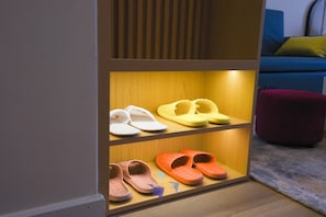 A wooden shoe rack with three shelves holding white, yellow, and orange slippers. - ICON40 Ha Long  Managed by Anstay (Bai Chay)