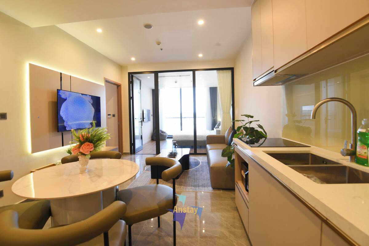 Una cocina moderna con horno integrado, un fregadero y un comedor con una mesa redonda y sillas.