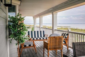 A covered porch with wicker furniture and a view of the water.