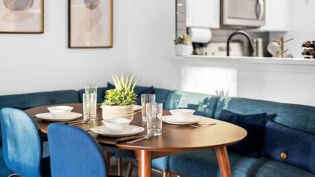 Un comedor moderno con una mesa redonda, sillas tapizadas en azul y un sofá azul.