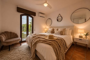 A bedroom with a bed, a chair, a bedside table, and a ceiling fan. - Los Arcos | Charming Patio Pool Townhouse (Marbella)