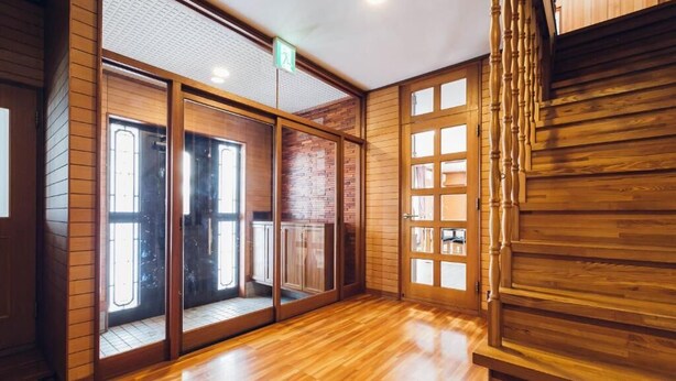 A room with wooden flooring, a staircase, and a sliding glass door leading to a balcony. - STAY IN SUEHIRO (Asahikawa)