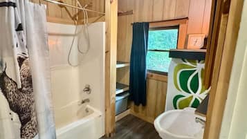 Ein kleines Badezimmer aus Holz mit Badewanne, Toilette und Waschbecken.