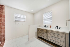A modern bathroom with two sinks, a vanity, and a large mirror.
