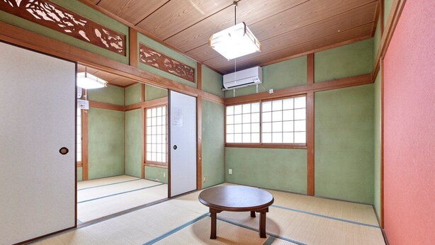 Een traditionele Japanse kamer met tatami vloerbedekking, een houten tafel, schuifdeuren en een groot raam.