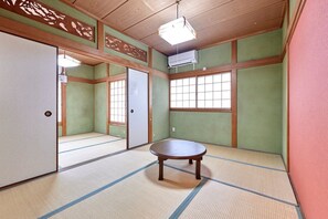 A traditional Japanese room with tatami flooring, a wooden table, sliding doors, and a large window.