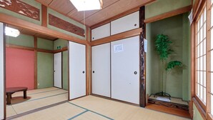 Een traditionele Japanse kamer met tatami vloeren, schuifdeuren en een klein bankje.