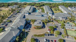 An aerial view of a coastal hotel with multiple buildings, parking areas, and a view of the ocean. - The Pool Resort Kingscliff - One Bedroom (7106) - Holiday Management Co. (Tweed)