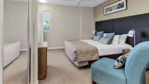 A bedroom with a bed, a chair, a nightstand, a ceiling fan, and a window with blinds. - The Pool Resort Kingscliff - One Bedroom (7106) - Holiday Management Co. (Tweed)