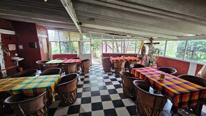 Un restaurante con suelo de cuadros, sillas de madera y mesas cubiertas con manteles de colores.