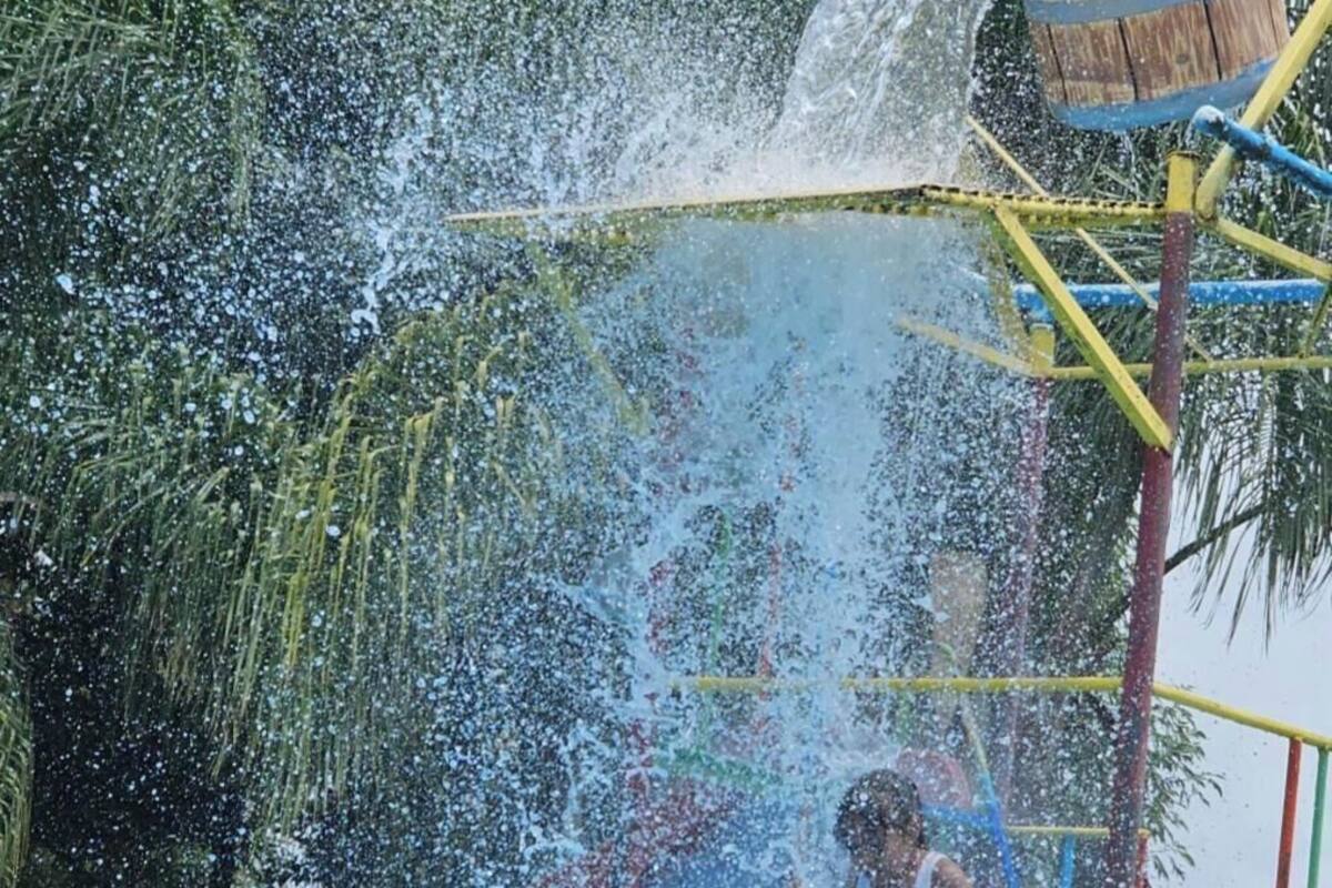 Un parque acuático con un tobogán azul y una fuente de agua.