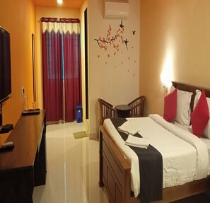 A hotel room with a bed, a desk, a chair, and a television. - Joe Beach Resort (Tirupporur)