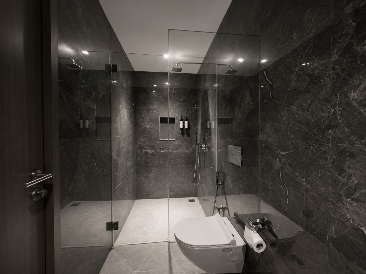 A modern bathroom with a glass-enclosed shower, a toilet, and a sink.