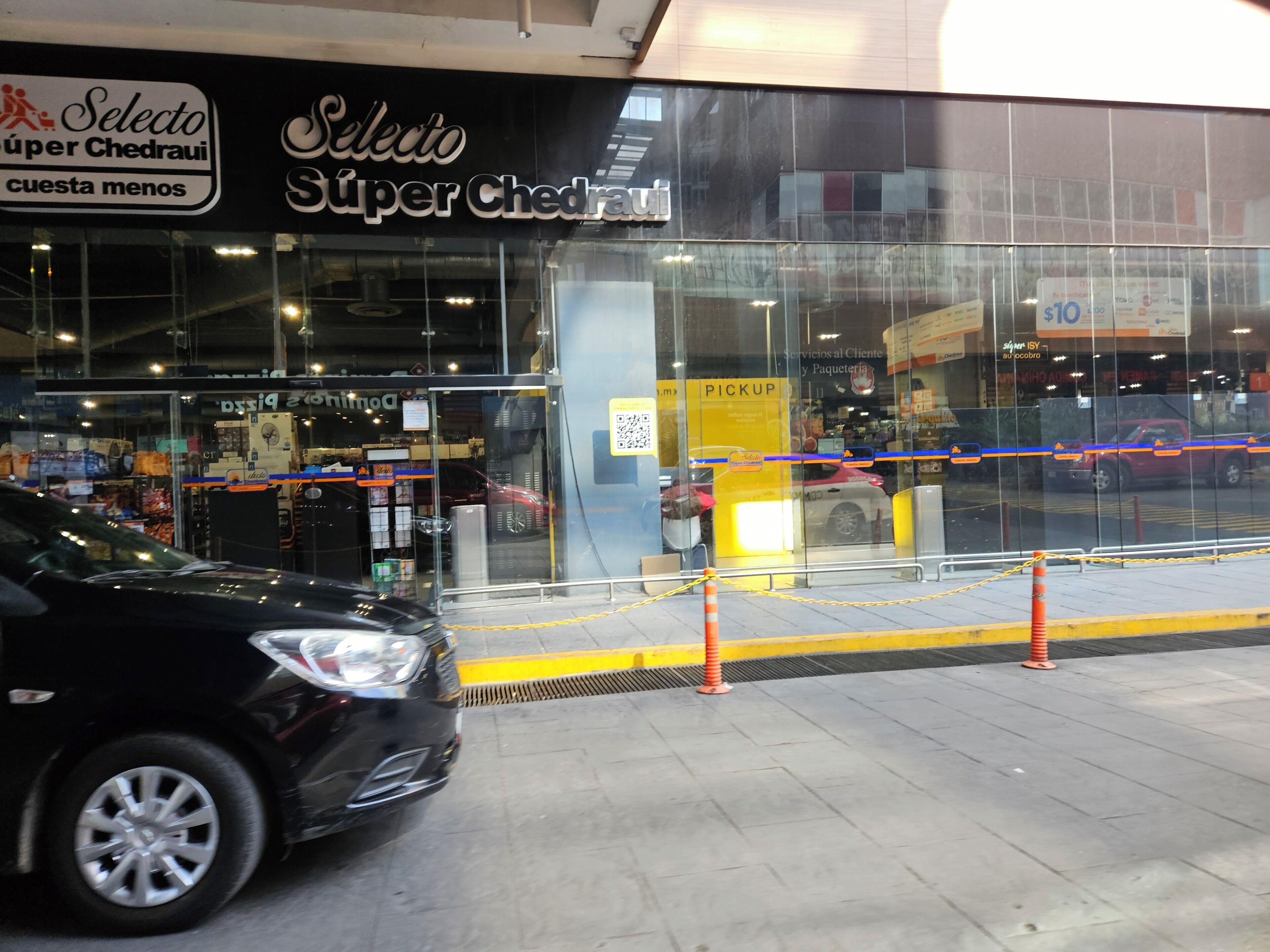 Une devanture de magasin avec une façade en verre, une enseigne indiquant « Selecto Super Cedravi » et un panneau jaune avec l’inscription « ENLÈVEMENT ».