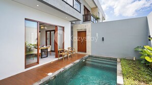 A modern house with a swimming pool, wooden deck, and a dining area with outdoor furniture. - deTasia Villa by Kozystay - Jimbaran (Jimbaran)