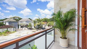 A balcony with a potted plant, a view of neighboring houses, and a clear sky. - deTasia Villa by Kozystay - Jimbaran (Jimbaran)