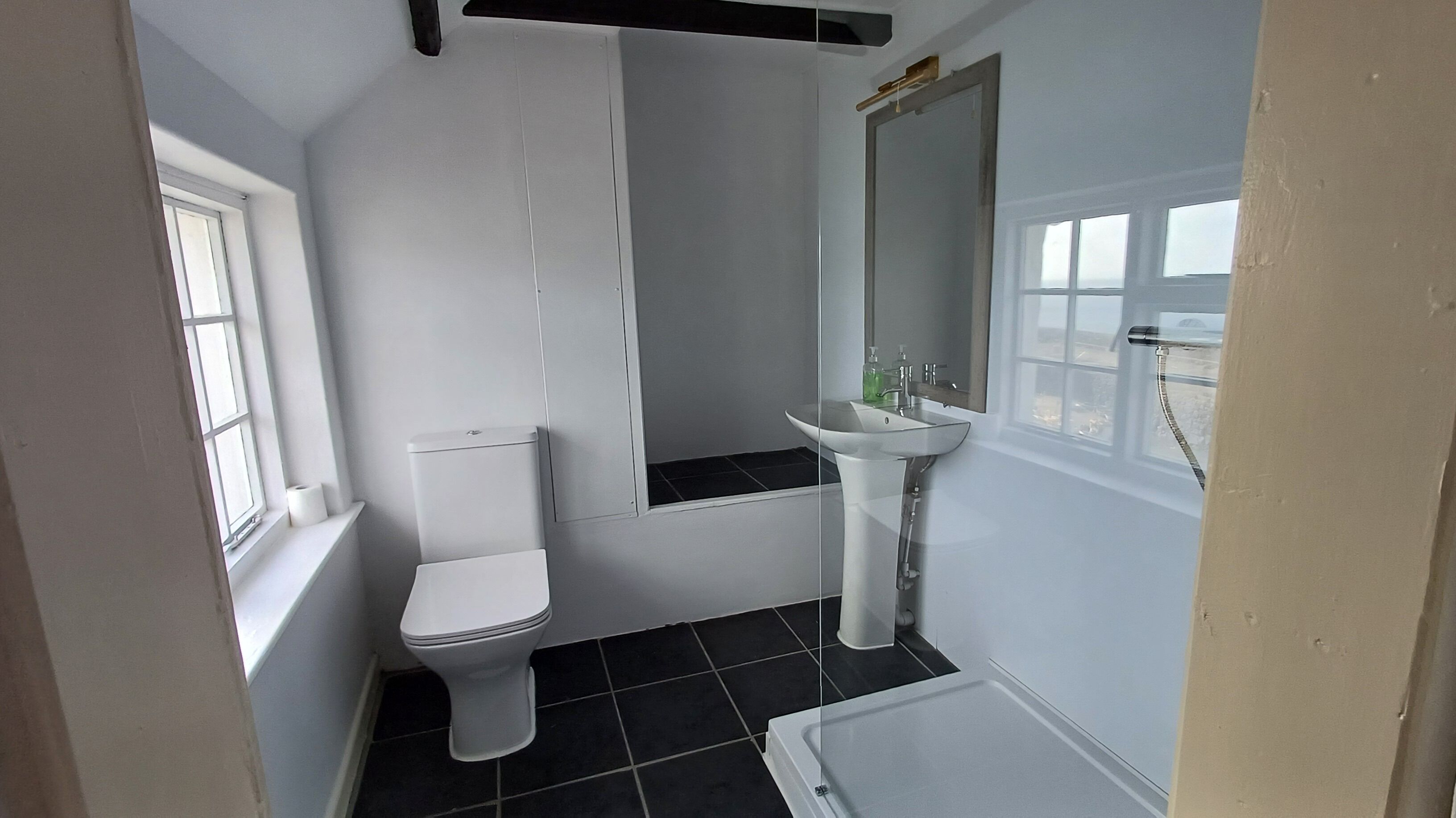 A small, compact bathroom with a toilet, sink, and shower.