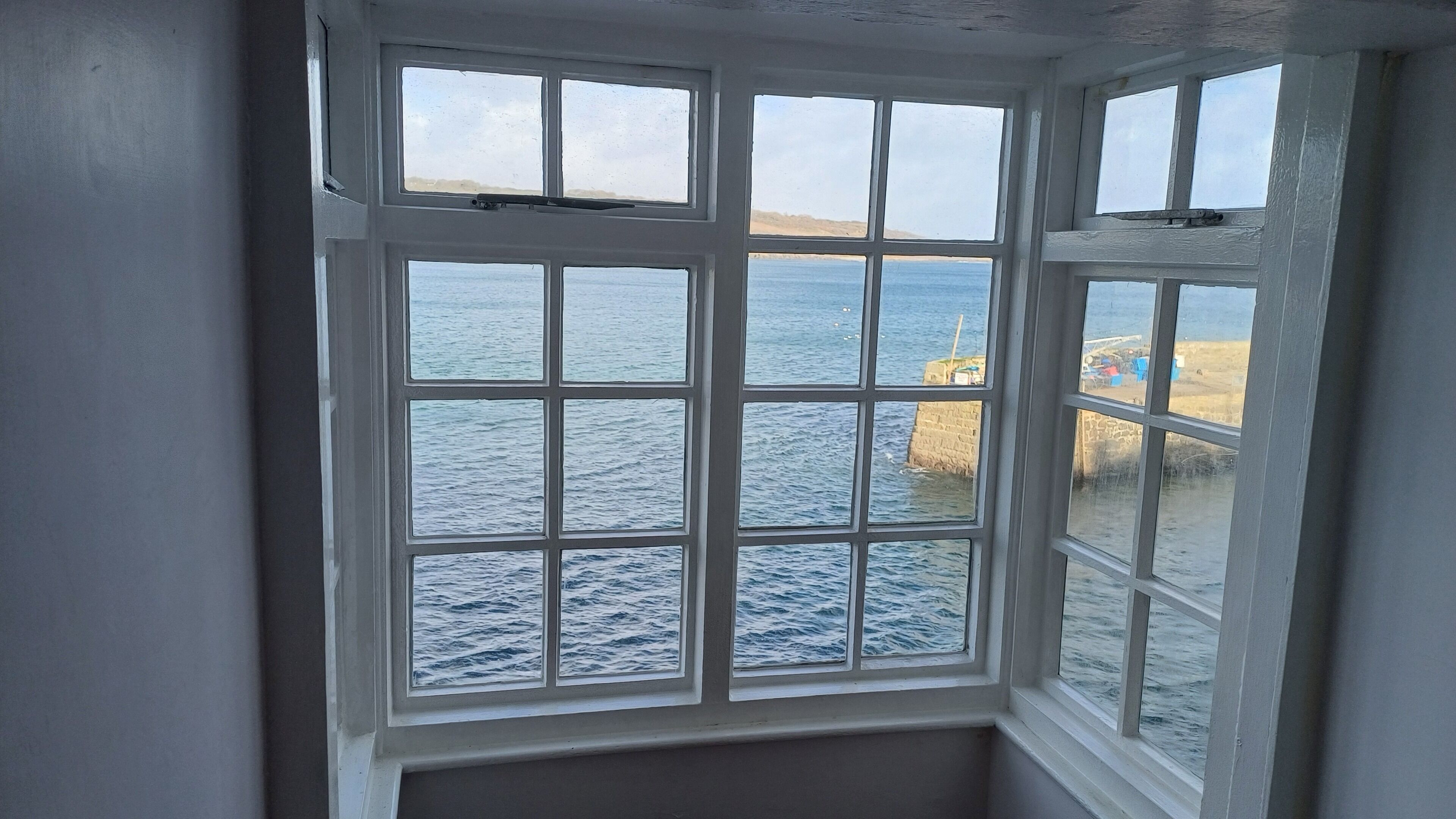 A window with a view of the sea and a rocky shoreline.