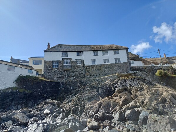 Un bâtiment blanc doté de nombreuses fenêtres et d’un socle en pierre, situé sur une côte rocheuse.