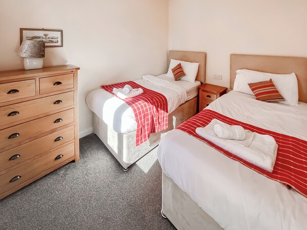 A hotel room with two beds, a wooden dresser, and a framed picture on the wall.