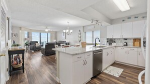 A spacious kitchen with white cabinets, a central island, and a dining area with a sofa and chairs. - Oceanfront Luxury 4BR | Sleeps 10 | Beach Club II (North Myrtle Beach)