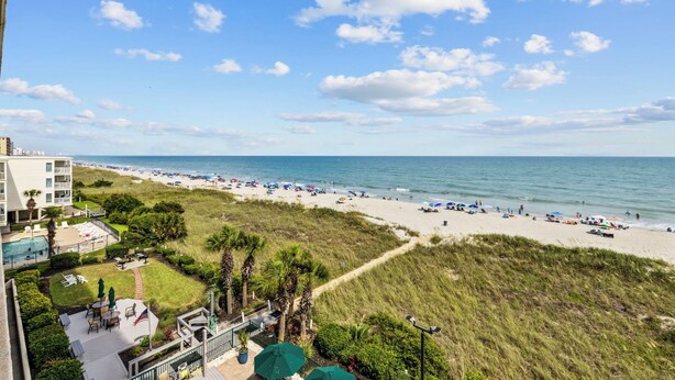 A beach view from a hotel balcony with a pool, lounge chairs, and umbrellas. - Oceanfront Luxury 4BR | Sleeps 10 | Beach Club II (North Myrtle Beach)