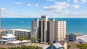 A multi-story hotel with balconies overlooking the ocean, a parking area, and a view of the beach. - Oceanfront Luxury 4BR | Sleeps 10 | Beach Club II (North Myrtle Beach)