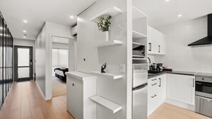 A modern kitchen with white cabinetry, stainless steel appliances, and a black range hood. - Charming Wānaka Apartment with Free Parking (Wānaka)