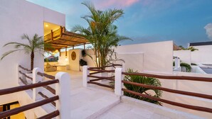 A modern outdoor area with a staircase, palm trees, and a covered seating area. - Villa Leblanc (Canggu)