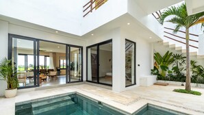 A modern house with a swimming pool, large glass doors, and a staircase leading to an upper level. - Villa Leblanc (Canggu)