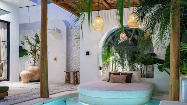 A circular outdoor seating area with a pool, surrounded by plants and a stone wall. - Villa Irie (Cemagi)