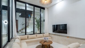 Una sala de estar moderna con un amplio sofá modular, una mesa de centro redonda y un televisor de pantalla plana montado en la pared.