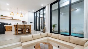 Una sala moderna con un sofá modular, una mesa de centro de madera y un comedor con mesa y sillas de madera.