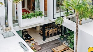 A modern multi-level living space with a dining area, lounge, and a small water feature. - Casa Ipanema (Kerobokan)