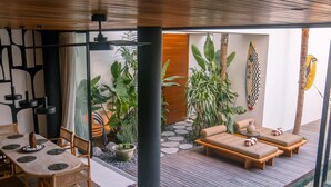 A modern indoor space with a dining area, seating area, and a view of the outdoors. - Casa Ipanema (Kerobokan)