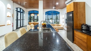 A modern kitchen with a central island, wooden cabinets, and a black refrigerator. - Villa Ambrogio A (Canggu)