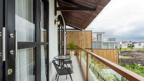 A balcony with a wooden railing, a glass door, and a table with chairs. - Villa Ambrogio B (Canggu)
