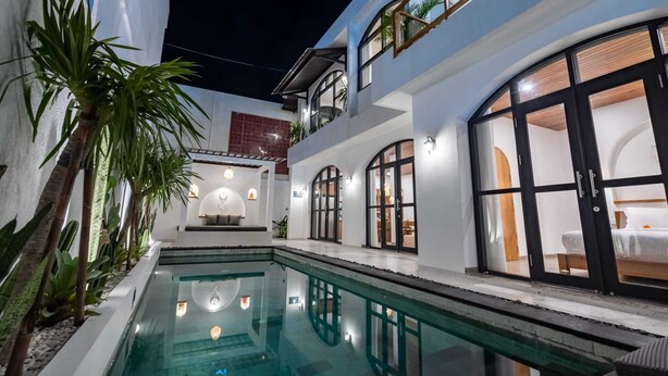 Et moderne hotel med swimmingpool, balkon og godt oplyst interiør.