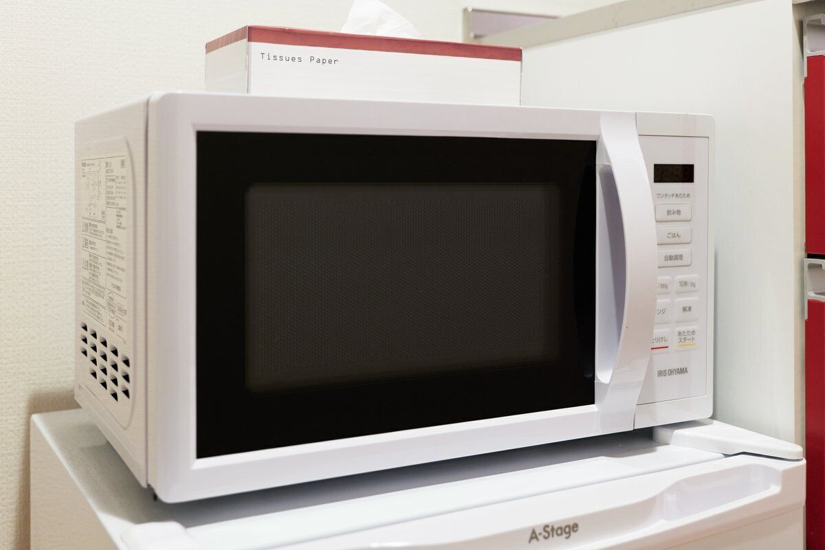 A white microwave oven with a digital display and control panel, placed on a white surface.