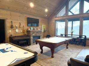A wooden interior with a pool table, a fireplace, and guitars on the wall. - Private Indoor Pool Cabin, Theater, Game Room, Hot Tub & Fire Pit (Gatlinburg)