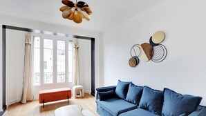 A modern living room with a blue sofa, a wooden coffee table, and a unique ceiling light fixture.