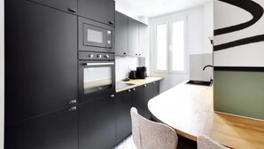 A modern kitchen with black cabinetry, a built-in oven, a microwave, and a coffee maker on the counter.