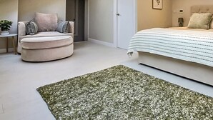 A modern bedroom with a skylight, a round sofa, a bed with a striped bedspread, and a green textured rug. - 5 bedroom accommodation in Halfpenny, near Kendal (Halfpenny, near Kendal)