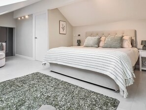 A modern bedroom with a large bed, a bedside table, a nightstand, a framed picture on the wall, and a door leading to another room. - 5 bedroom accommodation in Halfpenny, near Kendal (Halfpenny, near Kendal)