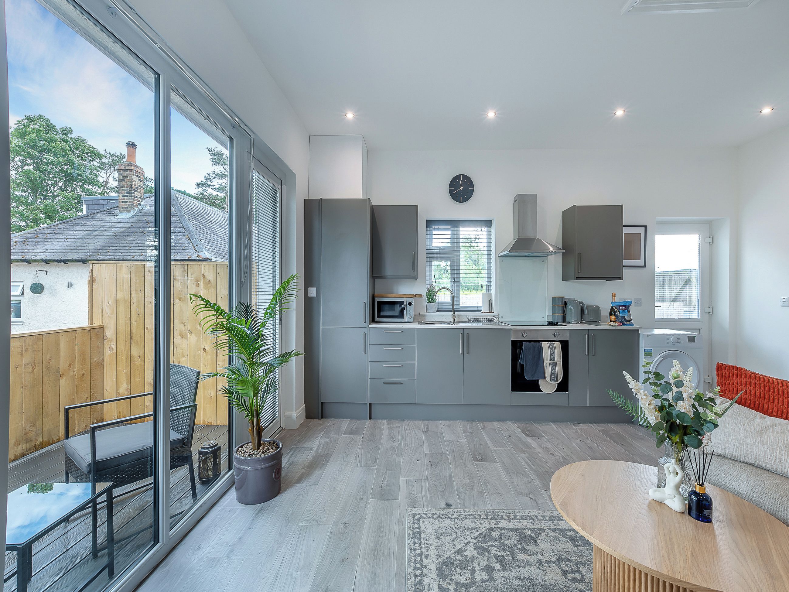 A modern kitchen with grey cabinets, a built-in microwave, and a large window.