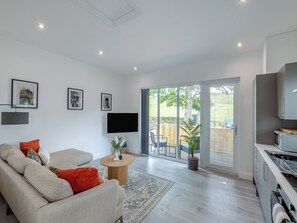 A modern living room with a sofa, a flat-screen TV, and a dining area with a table and chairs.